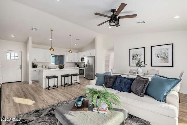 living room featuring ceiling fan, lofted ceiling, and light hardwood / wood-style floors