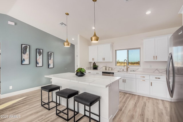 kitchen featuring pendant lighting, sink, light stone counters, white cabinets, and a kitchen island