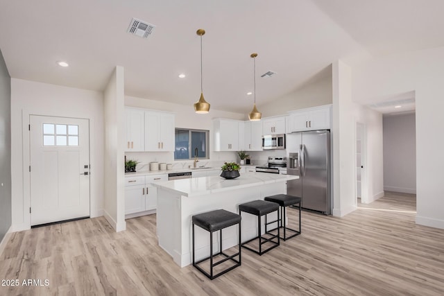 kitchen featuring sink, a center island, stainless steel appliances, light hardwood / wood-style floors, and white cabinets