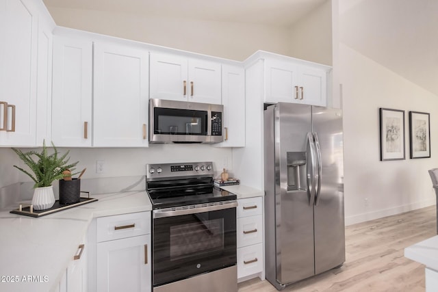 kitchen featuring light hardwood / wood-style flooring, stainless steel appliances, white cabinets, and vaulted ceiling