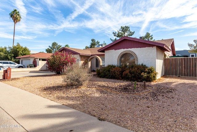 ranch-style home featuring driveway, fence, and stucco siding