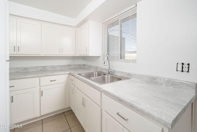 kitchen with light tile patterned flooring, white cabinetry, light countertops, and a sink