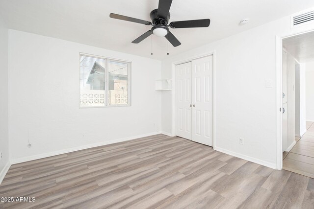 unfurnished bedroom with wood finished floors, visible vents, baseboards, ceiling fan, and a closet