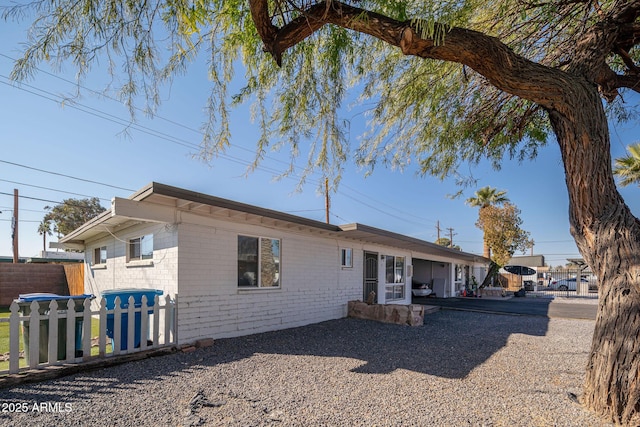 view of front of home featuring fence and brick siding