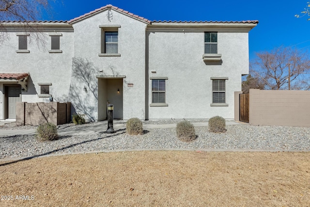 view of front of house featuring a tile roof, fence, and stucco siding