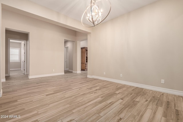 spare room featuring light hardwood / wood-style flooring and a notable chandelier