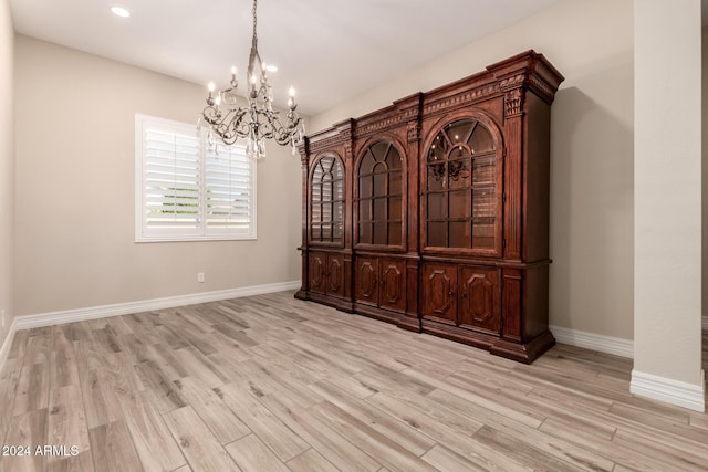 unfurnished dining area featuring an inviting chandelier and light hardwood / wood-style flooring