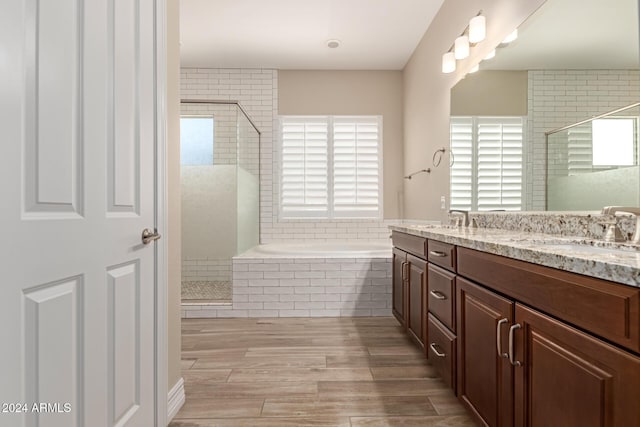 bathroom with plus walk in shower, wood-type flooring, and vanity