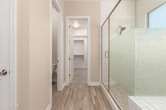 bathroom featuring toilet, a shower with door, and hardwood / wood-style flooring