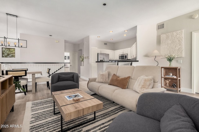 living room with an inviting chandelier and light hardwood / wood-style floors