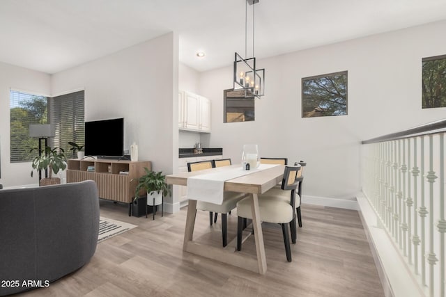 dining space with light hardwood / wood-style floors and a notable chandelier