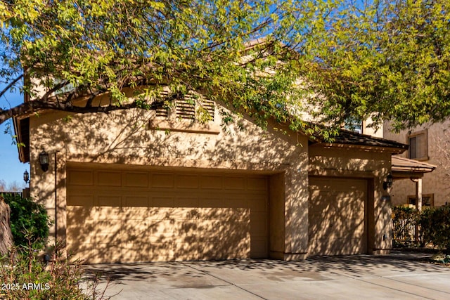 exterior space featuring an attached garage, driveway, and stucco siding