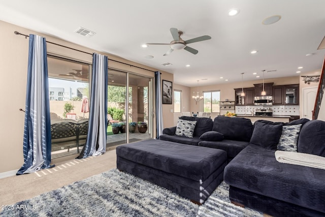 living area with recessed lighting, ceiling fan with notable chandelier, visible vents, and light carpet