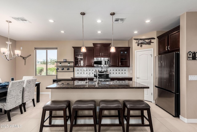 kitchen featuring dark brown cabinets, tasteful backsplash, appliances with stainless steel finishes, and a sink