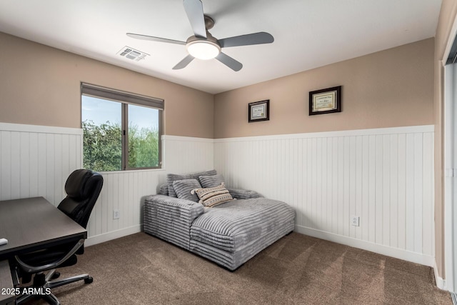 carpeted bedroom with visible vents, wainscoting, and ceiling fan