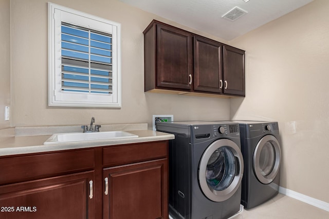 clothes washing area featuring light tile patterned floors, visible vents, cabinet space, a sink, and washer and dryer