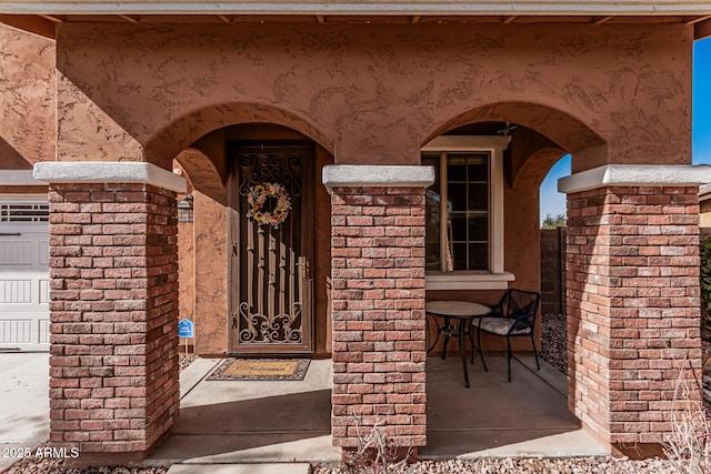 view of exterior entry with a garage and brick siding