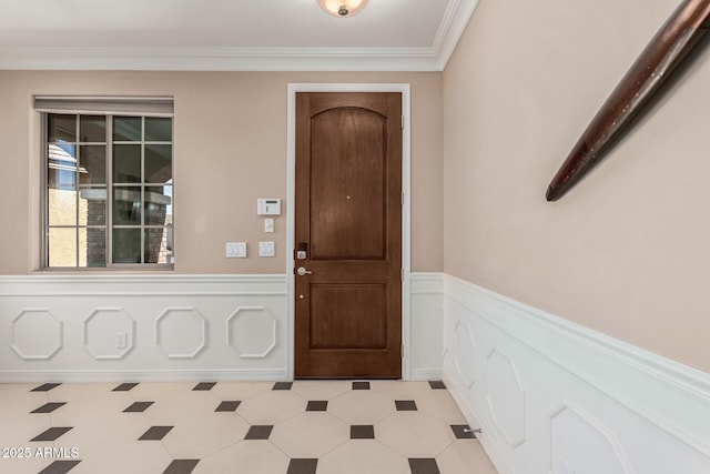 foyer entrance with wainscoting, crown molding, and light floors