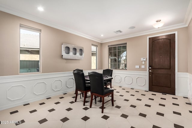 dining space with a decorative wall, visible vents, and ornamental molding