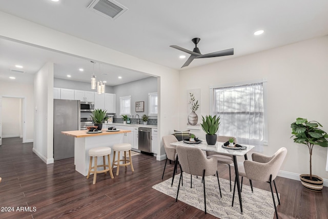 dining room with ceiling fan, sink, and dark wood-type flooring