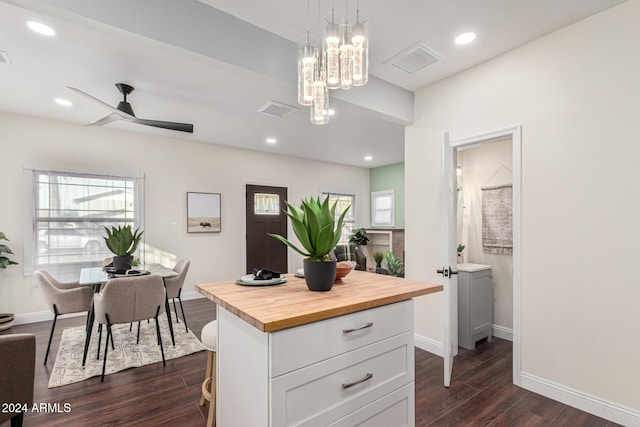 kitchen featuring wooden counters, ceiling fan with notable chandelier, dark wood-type flooring, pendant lighting, and white cabinetry