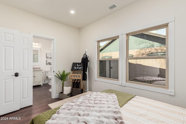 bedroom with ensuite bath and dark hardwood / wood-style floors