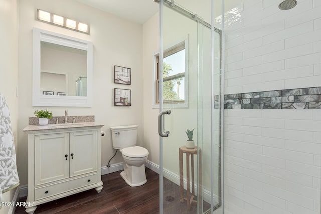 bathroom with toilet, a shower with door, vanity, and hardwood / wood-style flooring