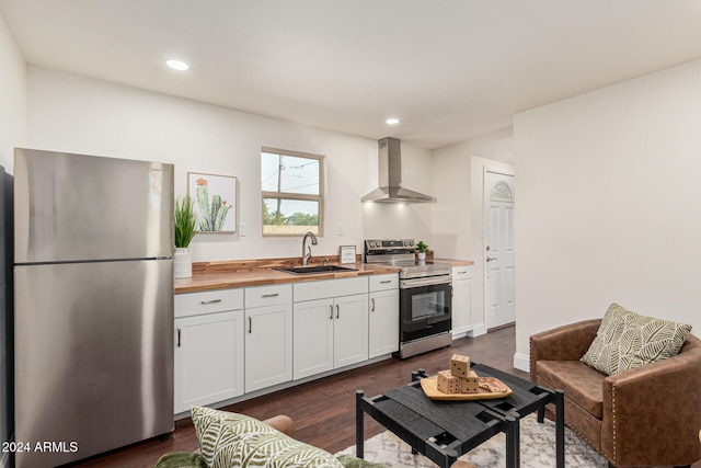 kitchen featuring sink, stainless steel appliances, wall chimney range hood, wooden counters, and white cabinets