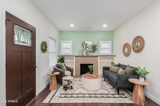 living room featuring dark hardwood / wood-style floors and a brick fireplace