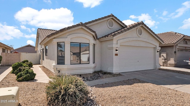 mediterranean / spanish house with a garage, fence, driveway, a tiled roof, and stucco siding