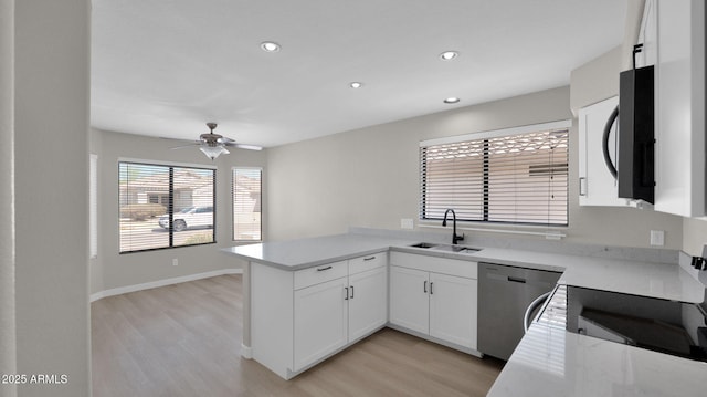 kitchen featuring stainless steel dishwasher, light wood-style floors, white cabinetry, a sink, and a peninsula