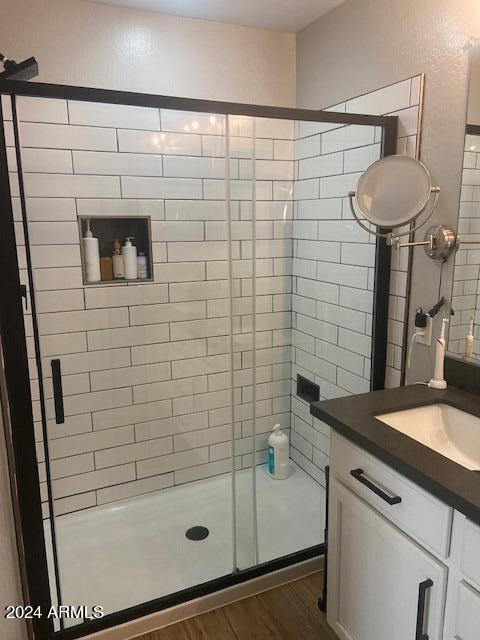 bathroom featuring vanity, a shower with shower door, and wood-type flooring