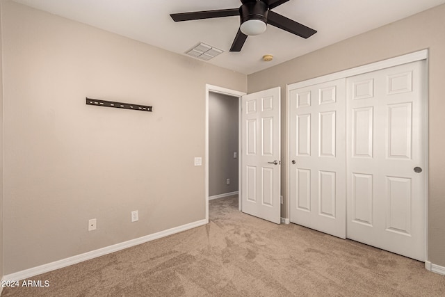 unfurnished bedroom with light colored carpet, a closet, and ceiling fan