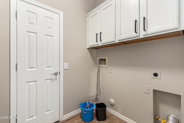 clothes washing area with hookup for an electric dryer, washer hookup, light hardwood / wood-style floors, and cabinets