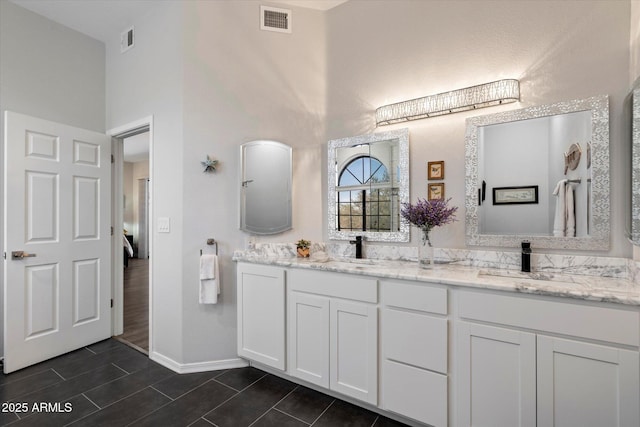bathroom with visible vents, a sink, and a towering ceiling