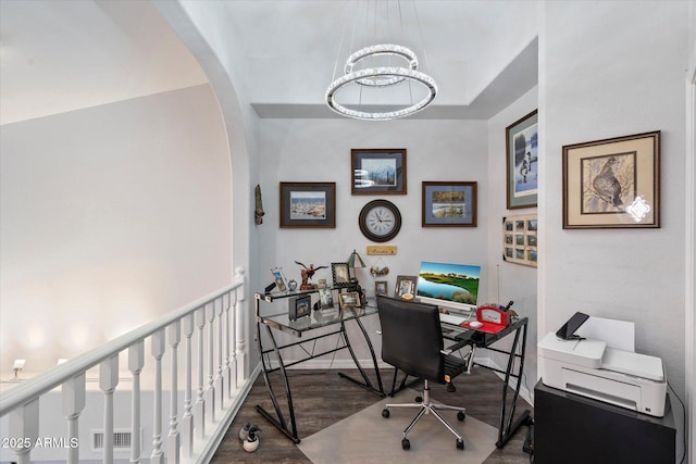 office space with arched walkways, wood finished floors, and a notable chandelier