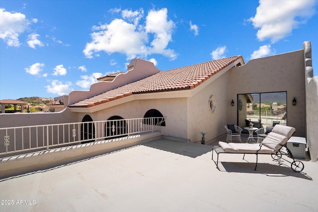 back of property with a tiled roof, a patio area, and stucco siding