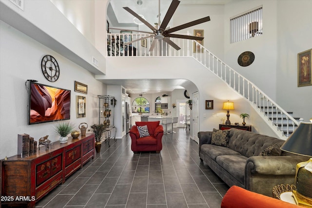 living room with visible vents, arched walkways, a towering ceiling, and a ceiling fan