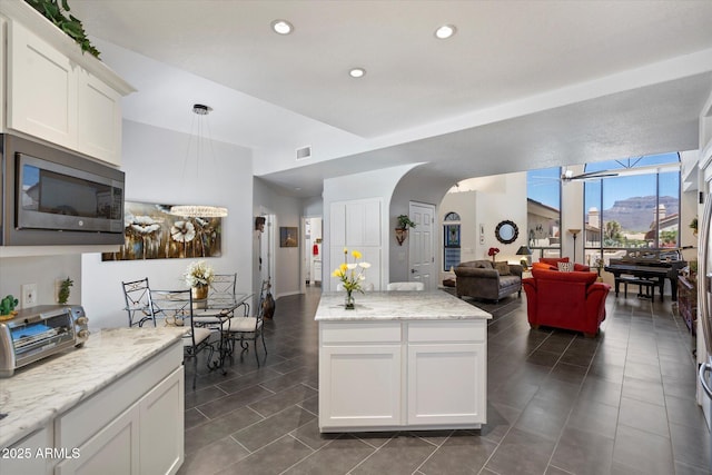 kitchen featuring visible vents, a toaster, stainless steel microwave, open floor plan, and white cabinetry