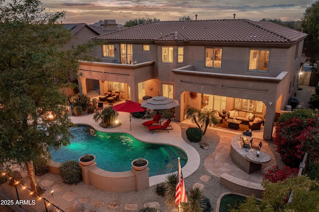 back house at dusk featuring an outdoor living space and a patio