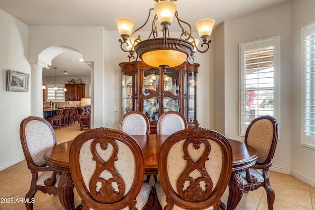 tiled dining area featuring decorative columns and a notable chandelier