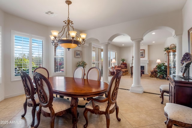 dining area featuring decorative columns, light tile patterned floors, and a notable chandelier