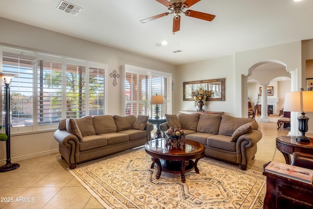 tiled living room with ceiling fan, a healthy amount of sunlight, and ornate columns