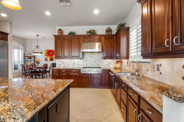 kitchen with pendant lighting, appliances with stainless steel finishes, dark stone counters, sink, and backsplash