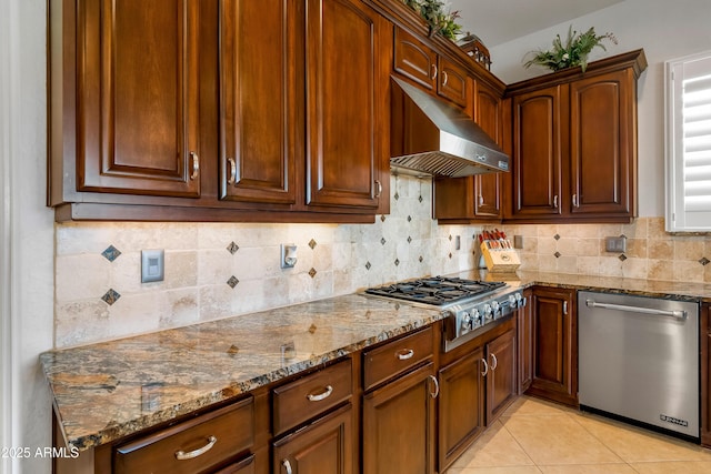 kitchen with light tile patterned floors, extractor fan, appliances with stainless steel finishes, backsplash, and stone counters