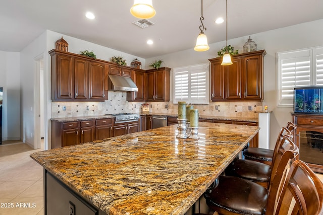 kitchen featuring light tile patterned flooring, appliances with stainless steel finishes, dark stone counters, and a kitchen island