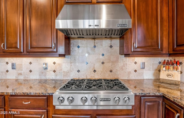 kitchen featuring ventilation hood, stainless steel gas cooktop, dark stone countertops, and tasteful backsplash