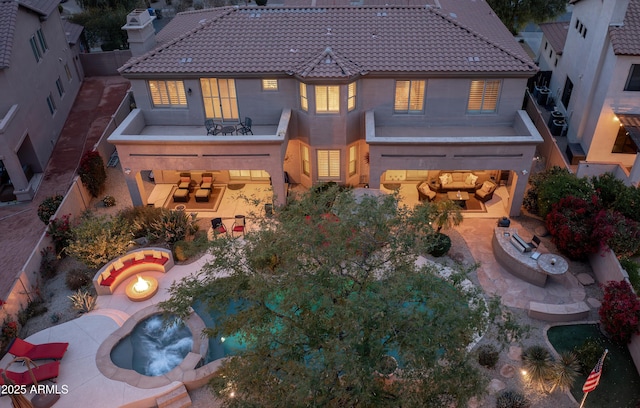 rear view of property with an outdoor fire pit, an in ground hot tub, and a patio