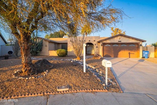 view of front of house with concrete driveway, fence, a garage, and stucco siding