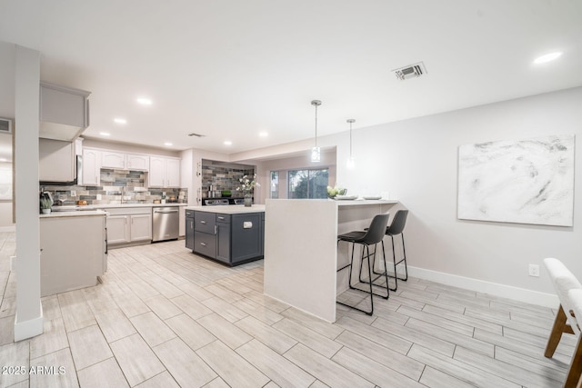 kitchen featuring visible vents, a kitchen island, light countertops, decorative backsplash, and dishwasher